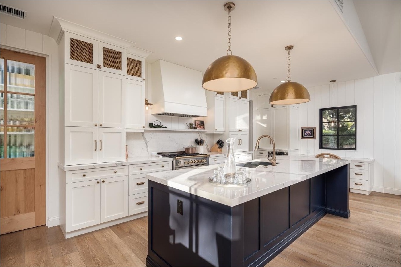 Guest house kitchen with navy island and brass dome pendants