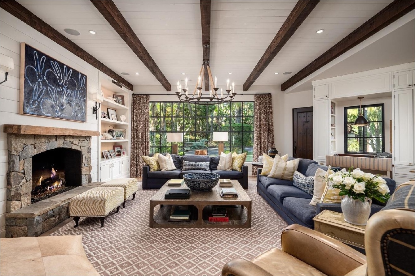 Living room with stone fireplace, wood beam ceiling, and navy sofas at the Rancho Santa Fe residence