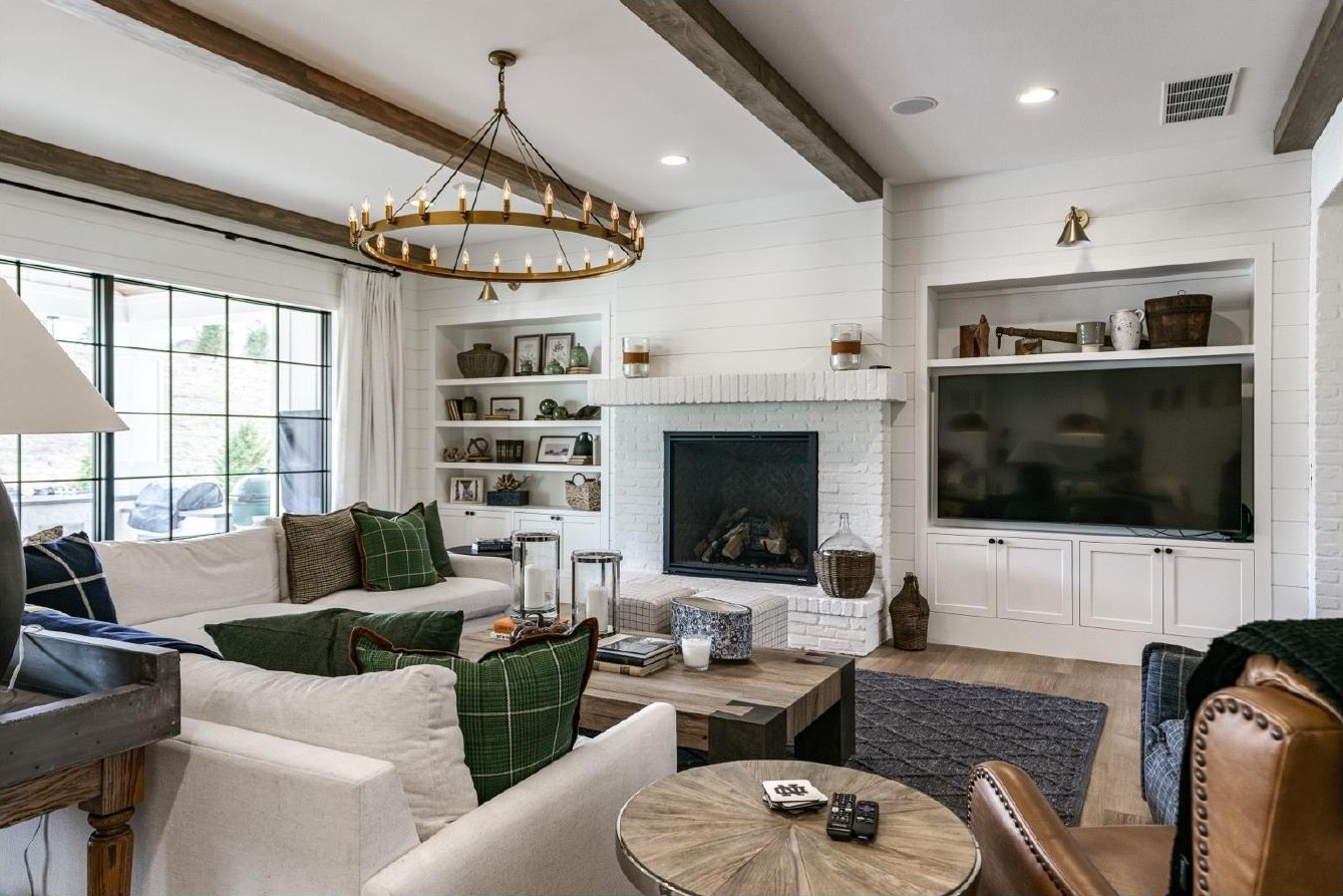 Family room with wood beams, brick fireplace, and circular chandelier at The Shamrock House