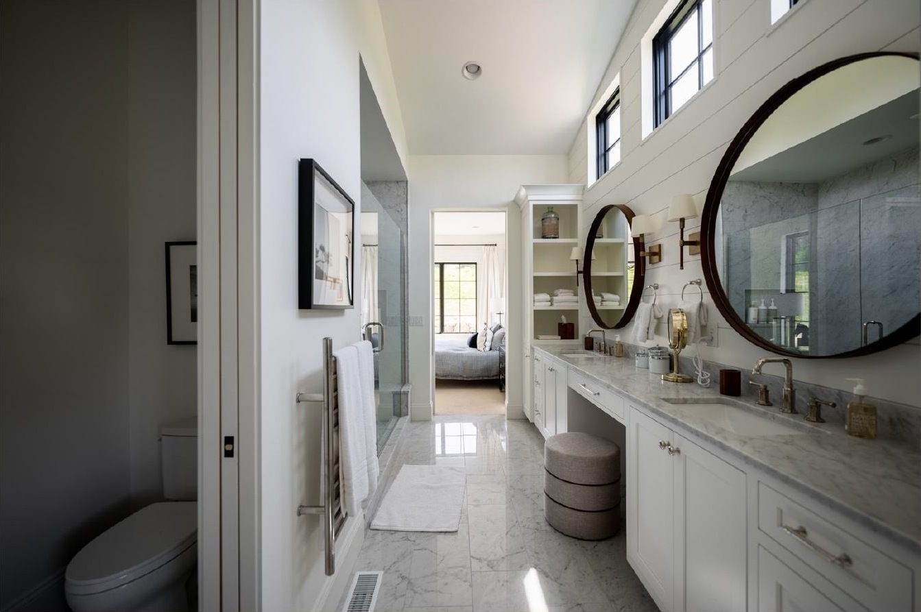 Primary bath hallway with round mirrors and marble floor